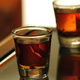 Two shots of deep mahogany brown whiskey shots on a wooden bar
